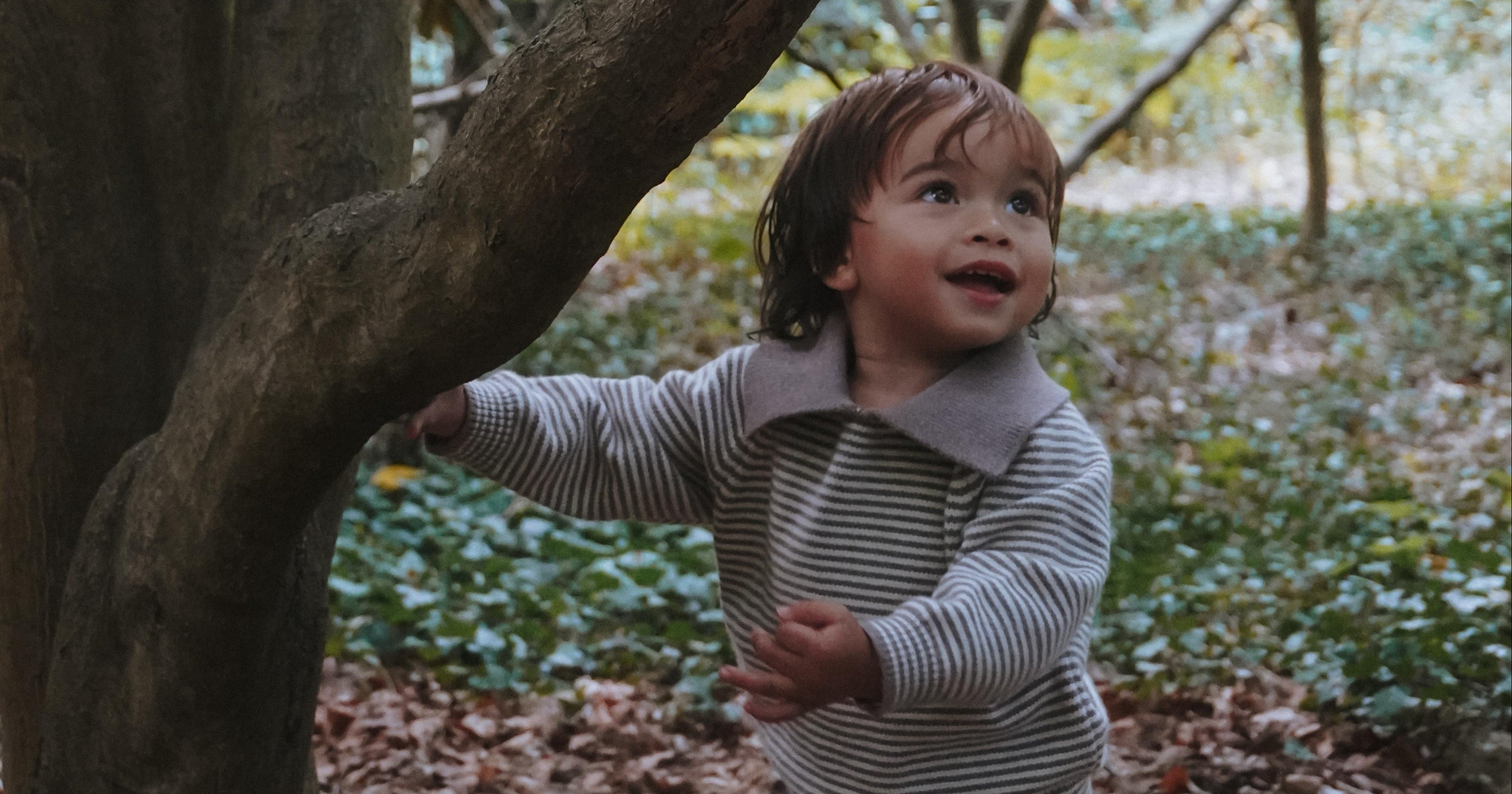 Child playing in a forest with trees and leaves